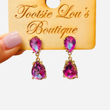 Gold-tone earrings with two stacked faceted pink teardrop crystals.