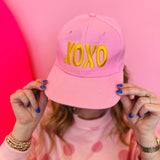 Pink XOXO embroidered baseball cap with gold lettering and adjustable snapback closure