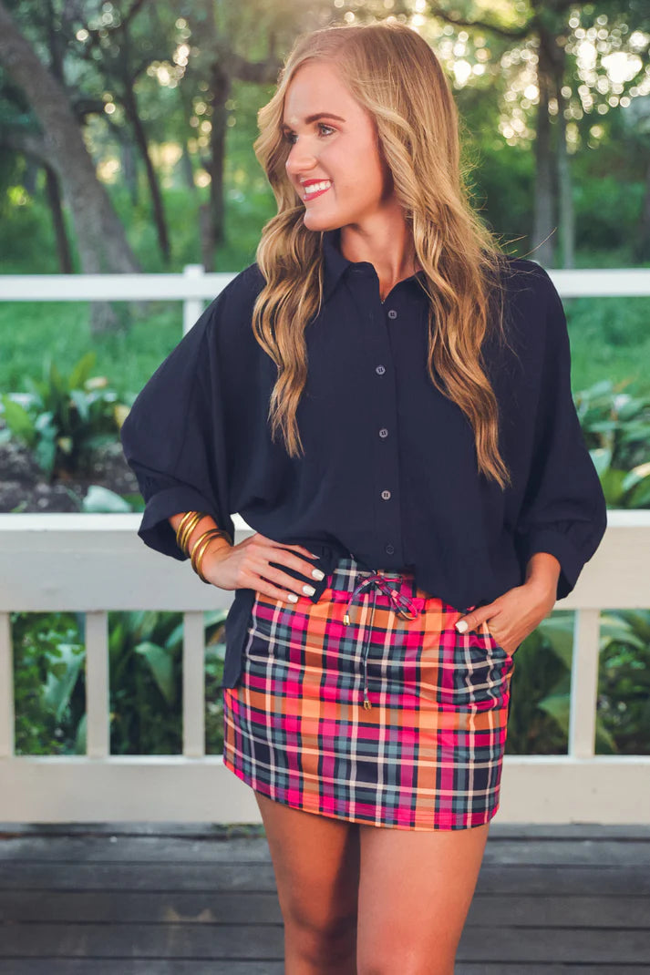 Patterned in Plaid Skort with navy, orange, and pink plaid design, elastic waistband, drawstring tie, built-in shorts, and side pockets in soft stretchy fabric.
