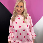 Light pink mockneck pullover with oversized hot pink polka dots and contrast trim.