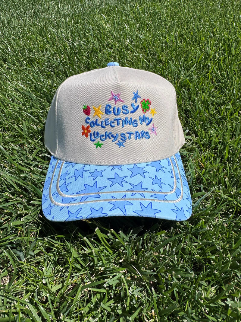 Off-white hat with lucky stars embroidery, strawberry accents, and blue star-print bill.
