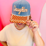 Poppy and Pine Denim-blue “Daughter” hat with brown polka dot bill, cream trim, and “of the King” side embroidery.