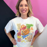 White cropped football tee with colorful game day collage, foam finger, stadium, and pennants.