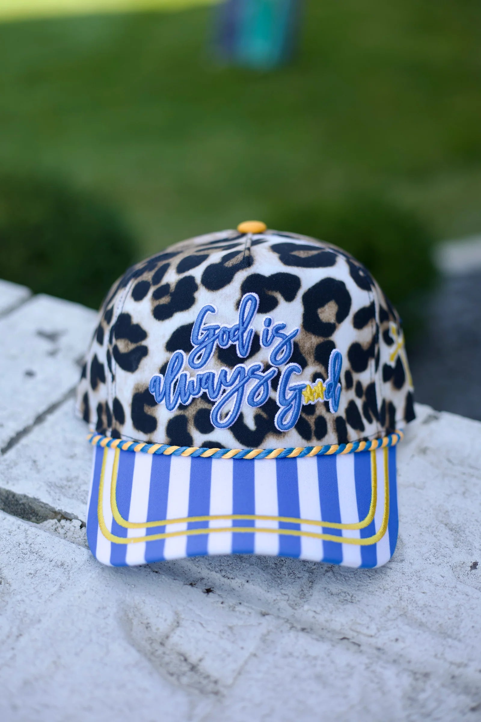 Leopard hat with God Is Always Good embroidery and blue striped bill.