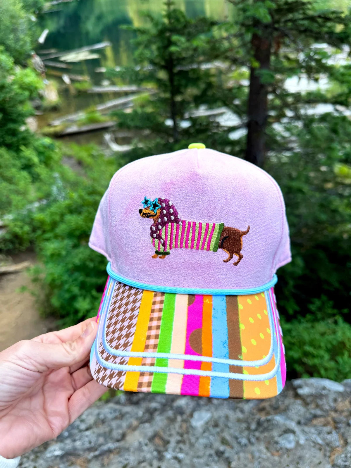 Lavender hat with embroidered dachshund, colorful sunglasses, mixed-print bill, and aqua piping.