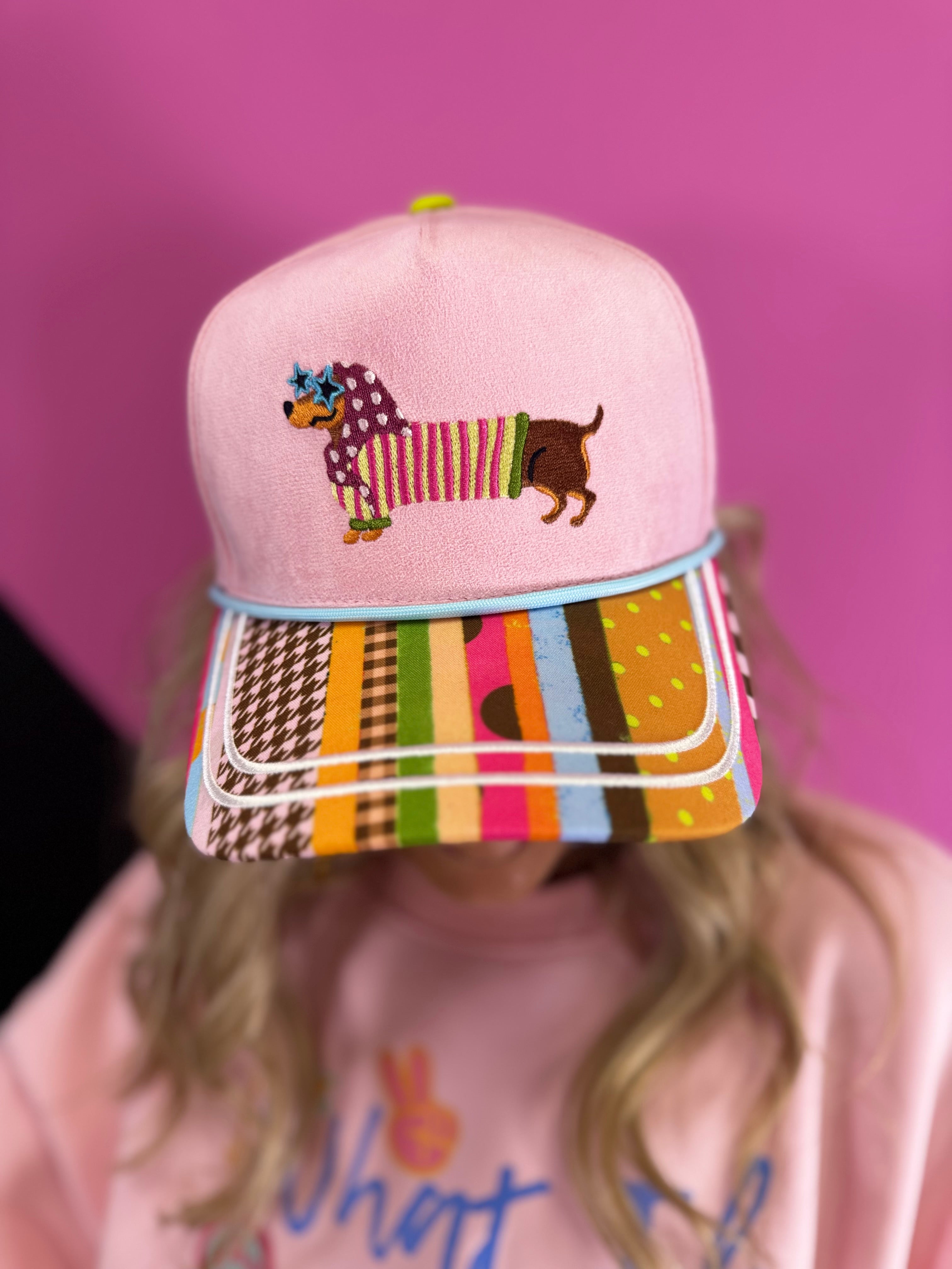 Lavender hat with embroidered dachshund, colorful sunglasses, mixed-print bill, and aqua piping.