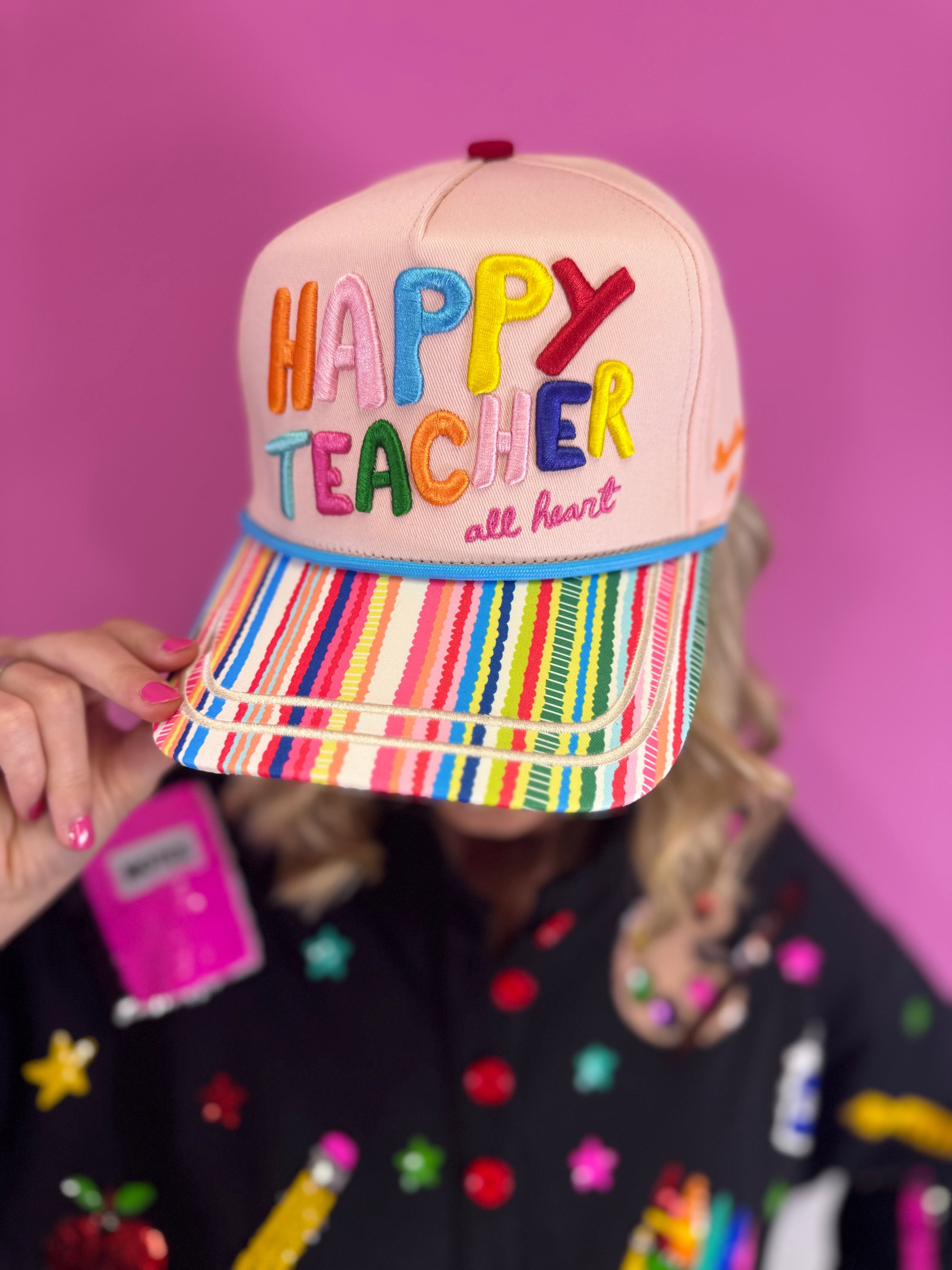 Neutral teacher hat with colorful Happy Teacher embroidery, striped bill, and classroom details.