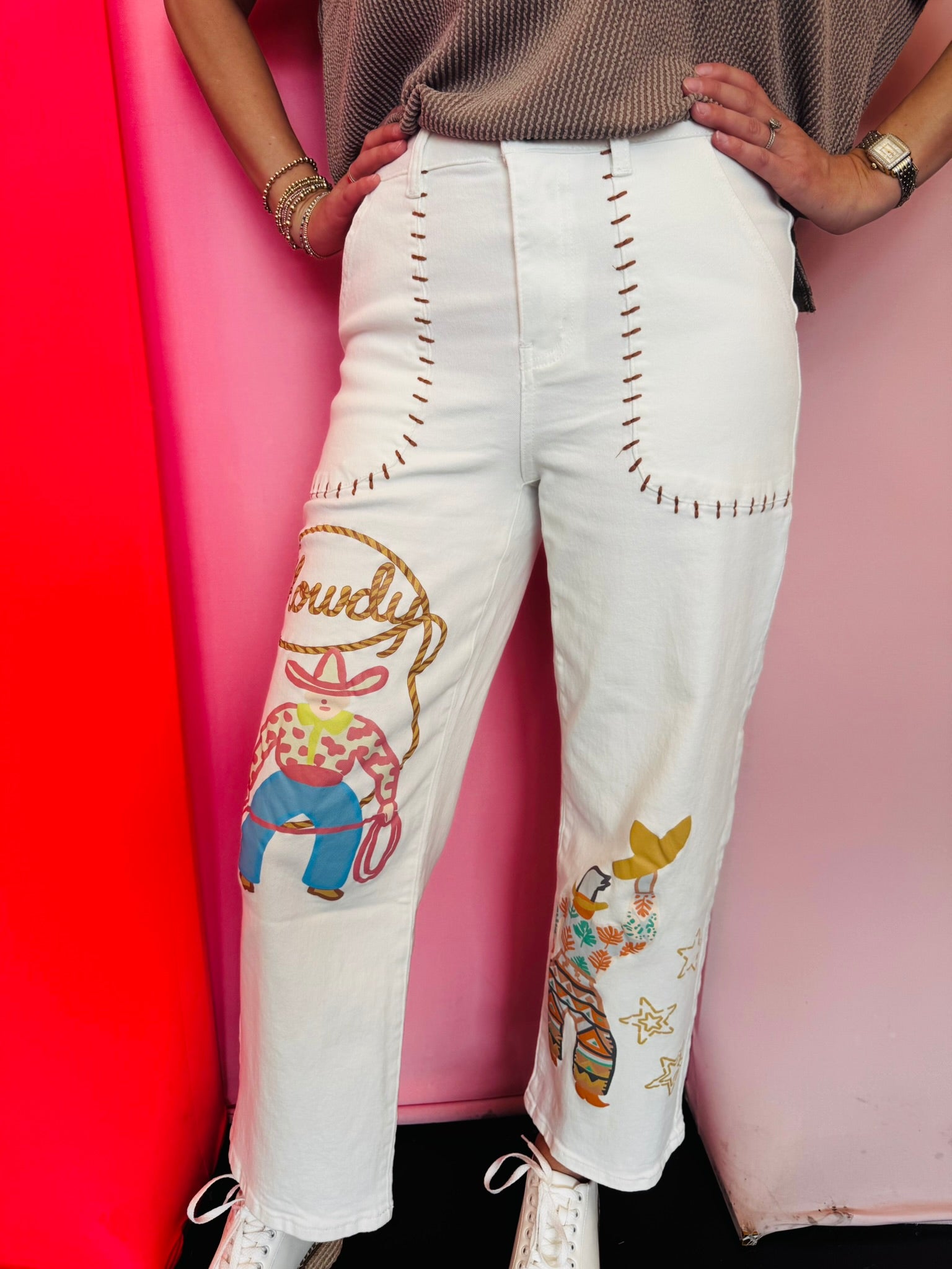 White wide-leg crop jeans with cowboy artwork and Western-inspired blanket stitch details.