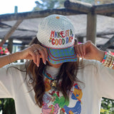 White hat with rainbow Make It a Good Day embroidery and colorful patterned bill.