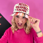 Cream teacher hat with black polka dots, colorful striped bill, embroidered lettering, stars, and A+ detail.