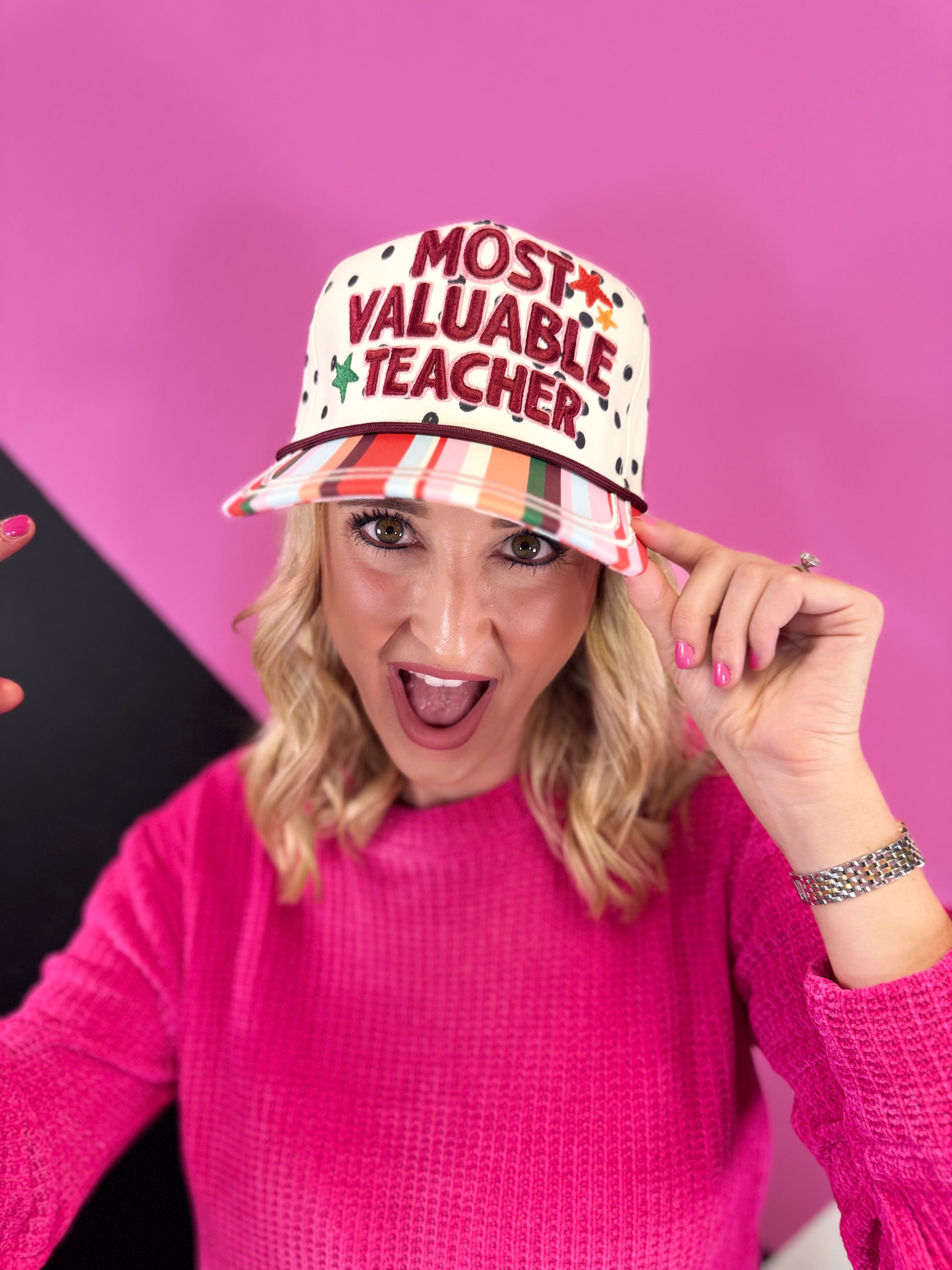 Cream teacher hat with black polka dots, colorful striped bill, embroidered lettering, stars, and A+ detail.