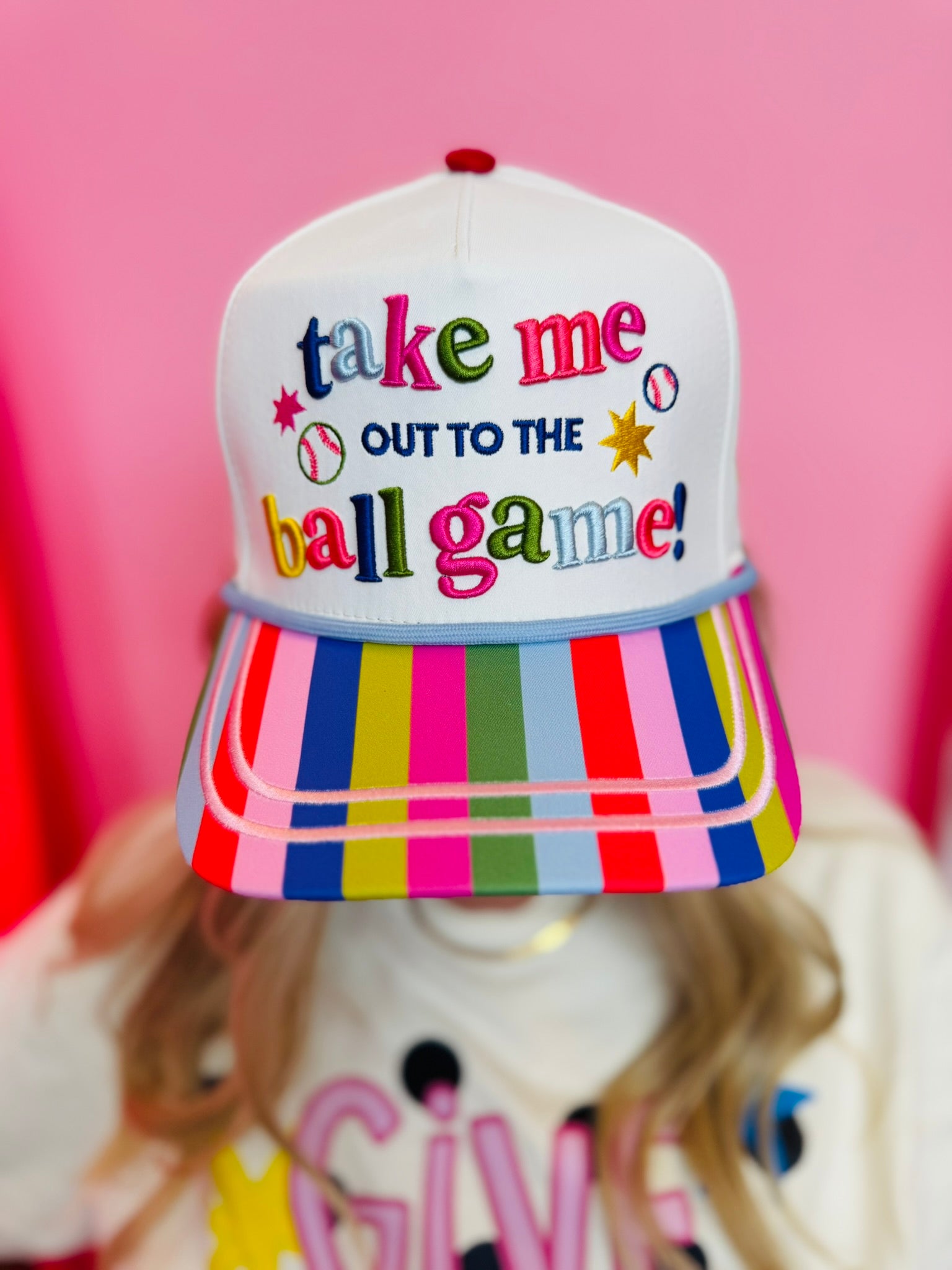 White baseball hat with colorful embroidery, striped bill, and ballpark-themed details.