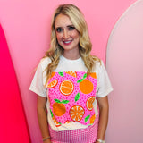 Cream tee with bright orange fruit graphic and bold pink design accents.