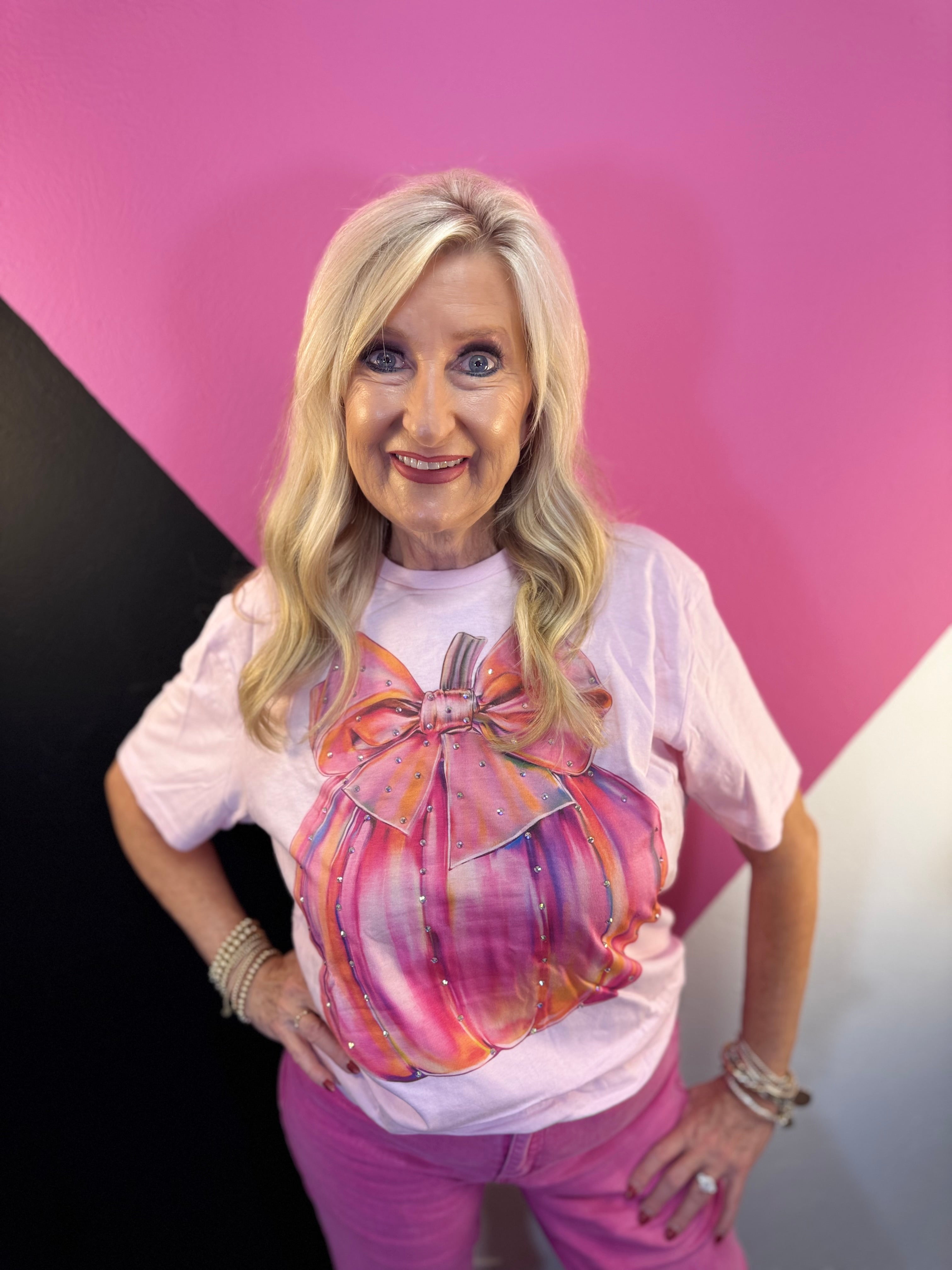 Pink tee with colorful pumpkin, oversized bow, and rhinestone accents.