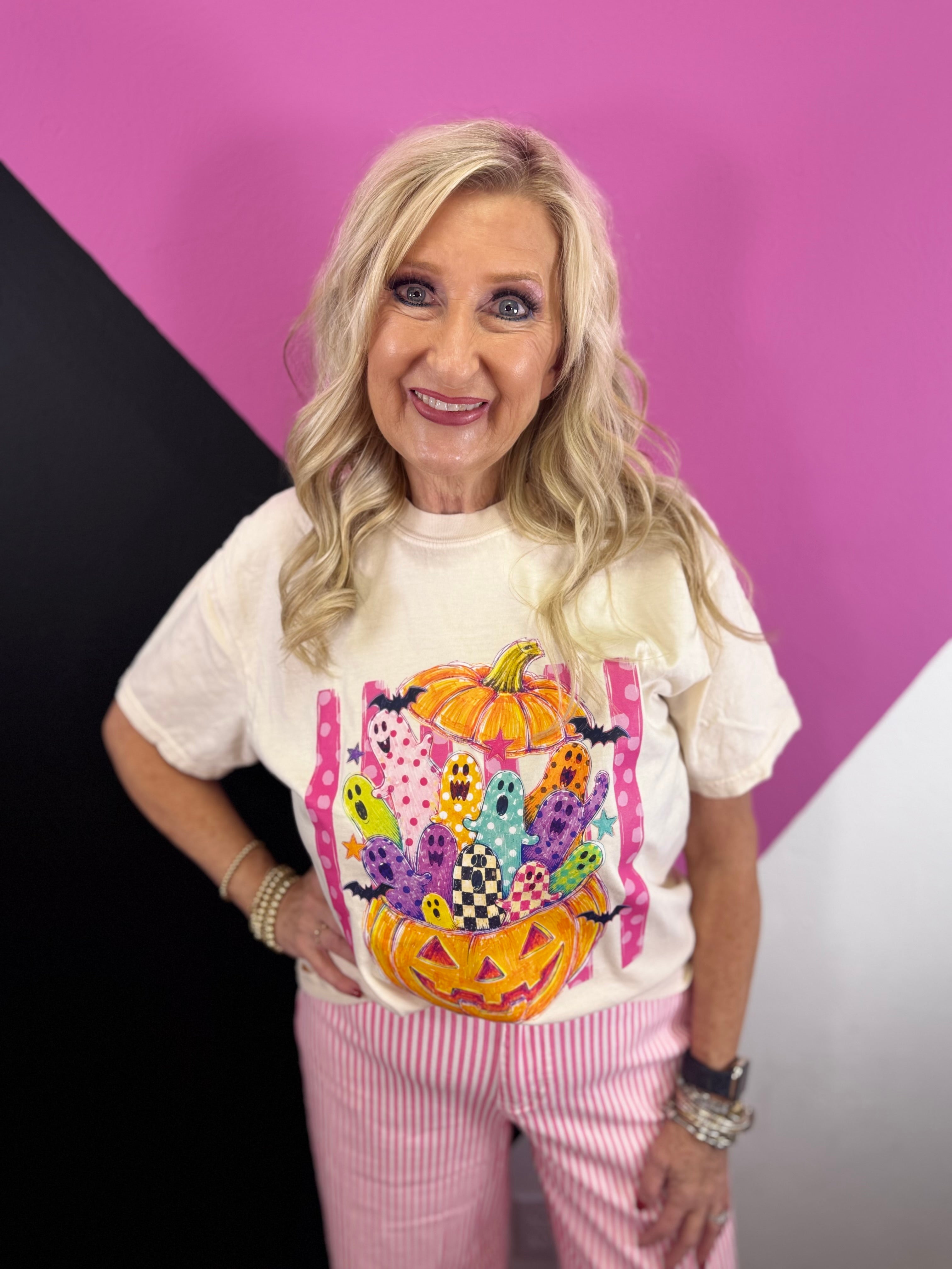 Colorful pumpkin graphic tee with playful ghosts, bats, pink stripes, and checkered details.