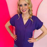 Purple woven V-neck blouse with cuffed short sleeves and lightweight flowy fabric