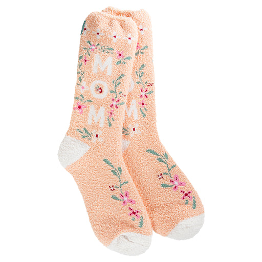 A pair of fuzzy, plush, peach-colored crew socks. The socks have small floral embroidery, and the word "MOM" is stitched across the front in a contrasting color.