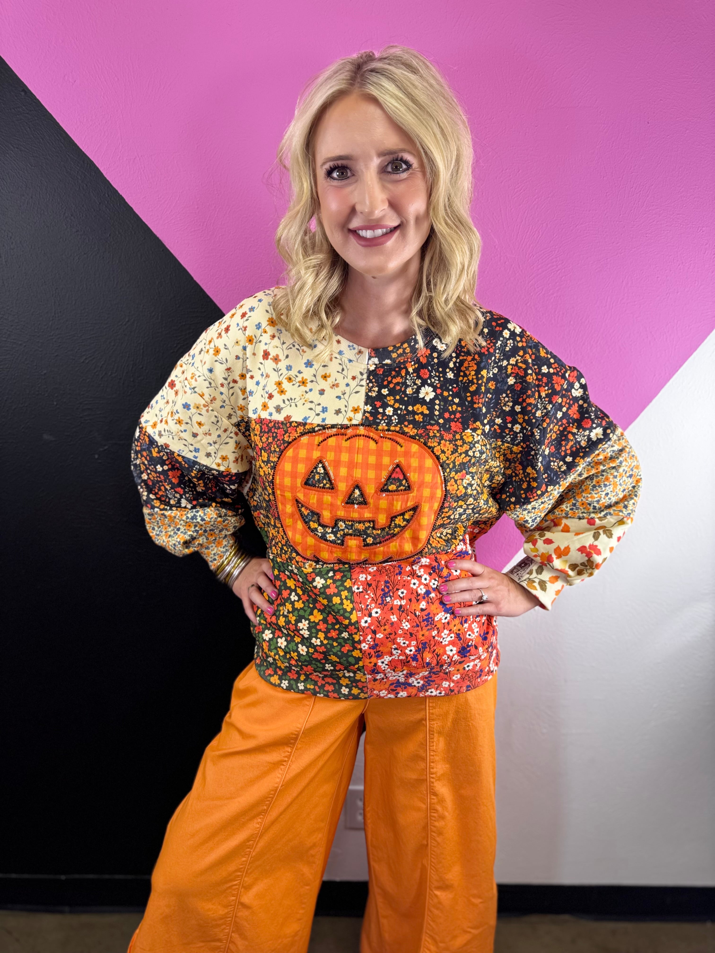 Colorful patchwork floral sweatshirt with oversized orange plaid jack-o'-lantern appliqué.