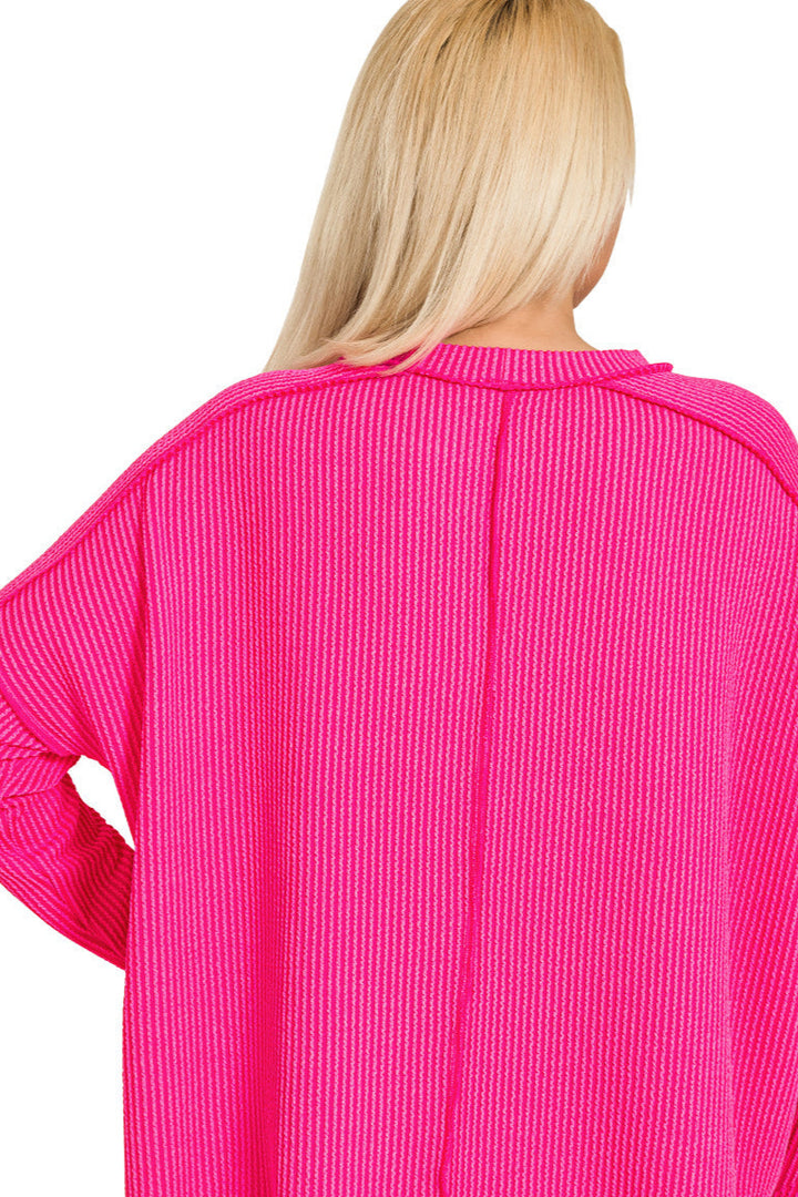 Plus-size hot pink ribbed boat neck top with raw edge detail and long sleeves.