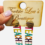 Multicolor “TEACHER” drop earrings hanging from textured gold stud.