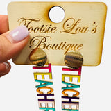 Multicolor “TEACHER” drop earrings hanging from textured gold stud.