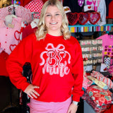 Red pullover sweatshirt with Be Mine applique, side slits, and bow detail.