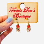 Red and clear gemstone drop earrings with gold hardware and faceted stones.