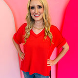 Red corded rib knit top with relaxed fit and hi-low V-neck.