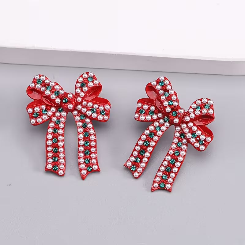 Red enamel bow stud earrings with pearl details and sparkling green rhinestone accents.