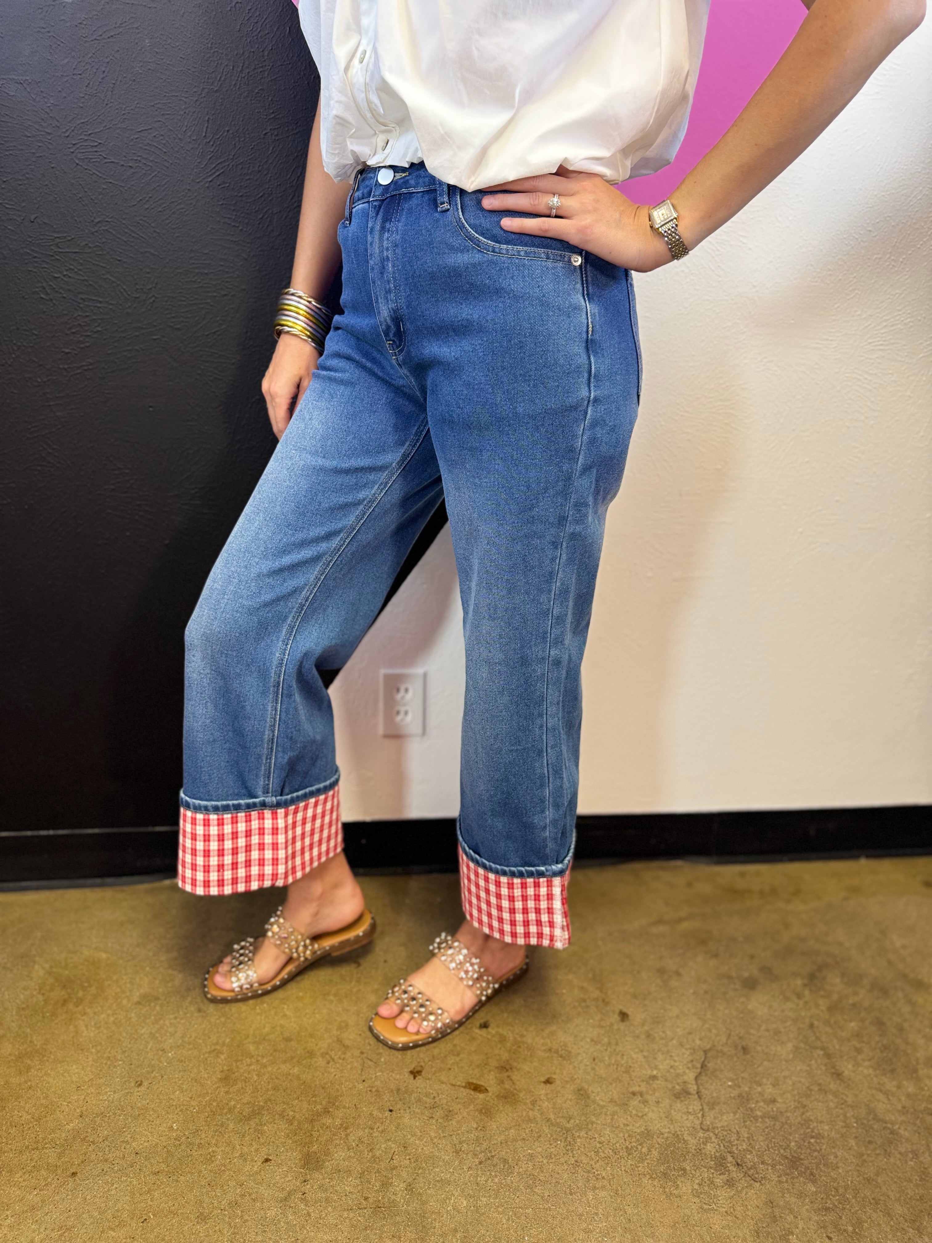 Medium wash straight-leg jeans with bold red and white gingham check cuffs.