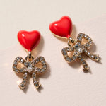 Glossy heart and rhinestone bow drop earrings with a cute, feminine sparkle design.