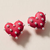 Red matte heart stud earrings covered in faux pearls for a bold, playful statement.