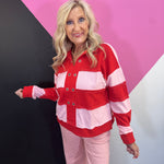 Red and pink striped pullover with grommet neckline, exposed seams, and long sleeves