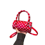 Red polka dot crossbody bag with adjustable strap and top handles.