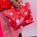 Red tote bag with oversized white polka dots and sturdy top handles.