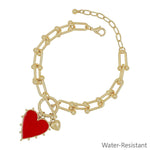 Gold chain bracelet with red studded heart charm featuring a bold water resistant design.
