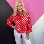 Red and white polka dot button down top with long sleeves and ruffle hem