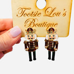 Nutcracker earrings with red glitter jackets, green glitter pants, and gold gem-accented crowns.