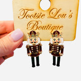 Nutcracker earrings with red glitter jackets, green glitter pants, and gold gem-accented crowns.