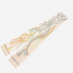 Reversible twilly scarf necklace with bold rope patterns, tassels, and golden chain floral motifs.