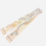 Reversible twilly scarf necklace with bold rope patterns, tassels, and golden chain floral motifs.