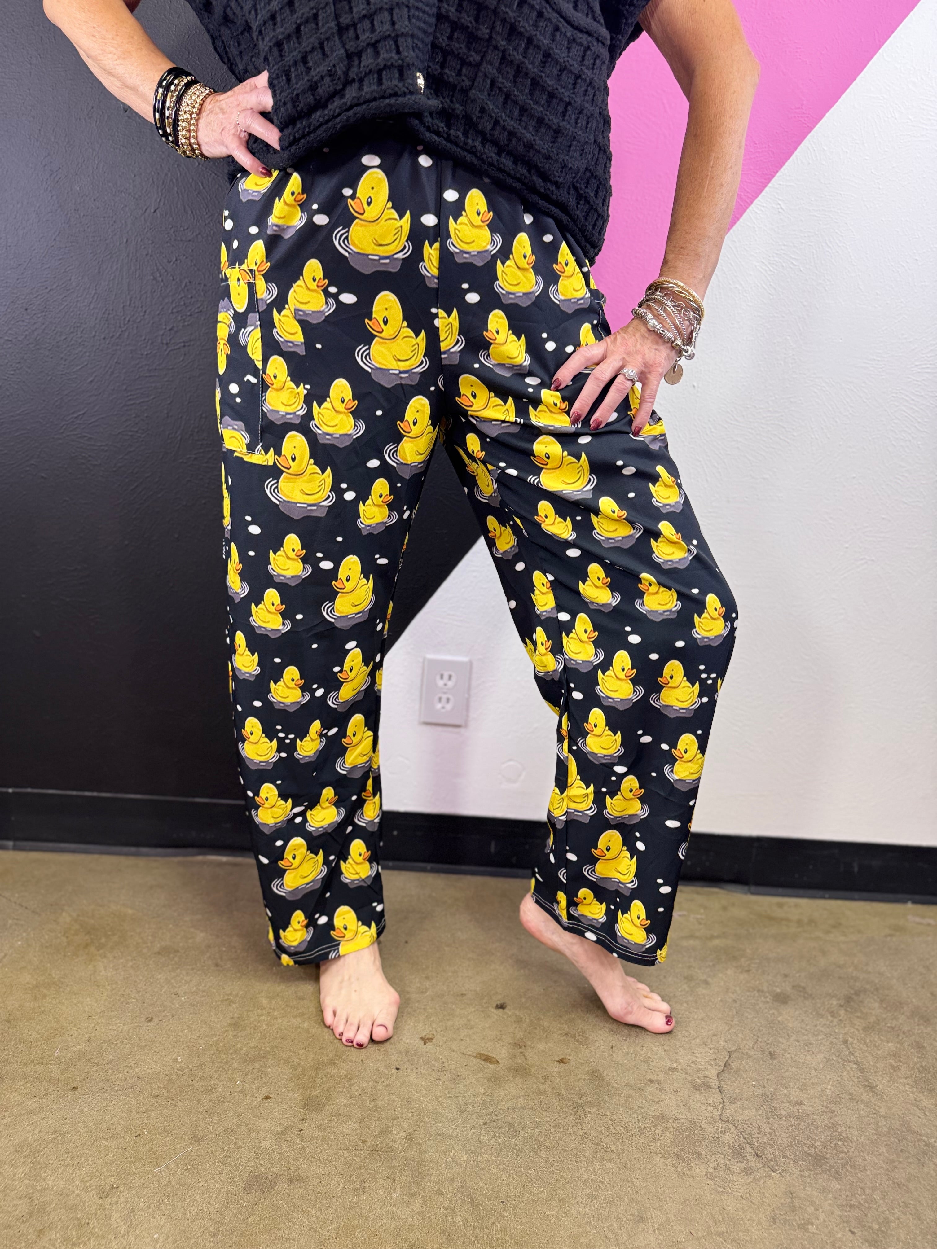 Black pants with bright yellow rubber ducks, white bubble accents, and elastic waistband.