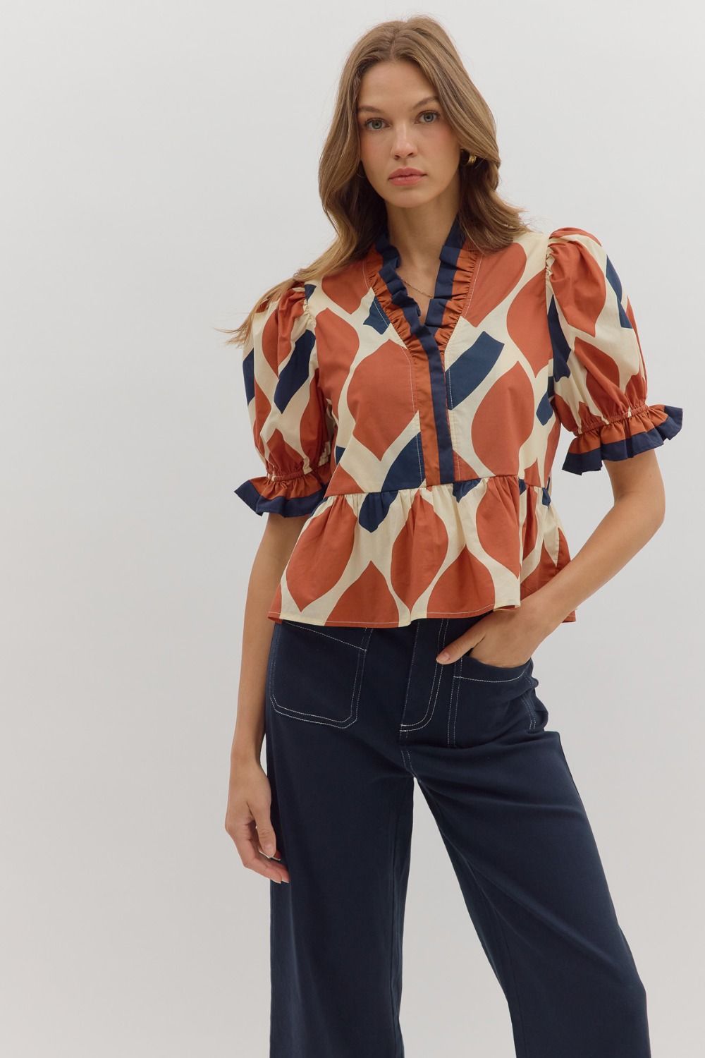 Rust abstract puff sleeve peplum top with ruffled trim, V-neckline, and flared hem.