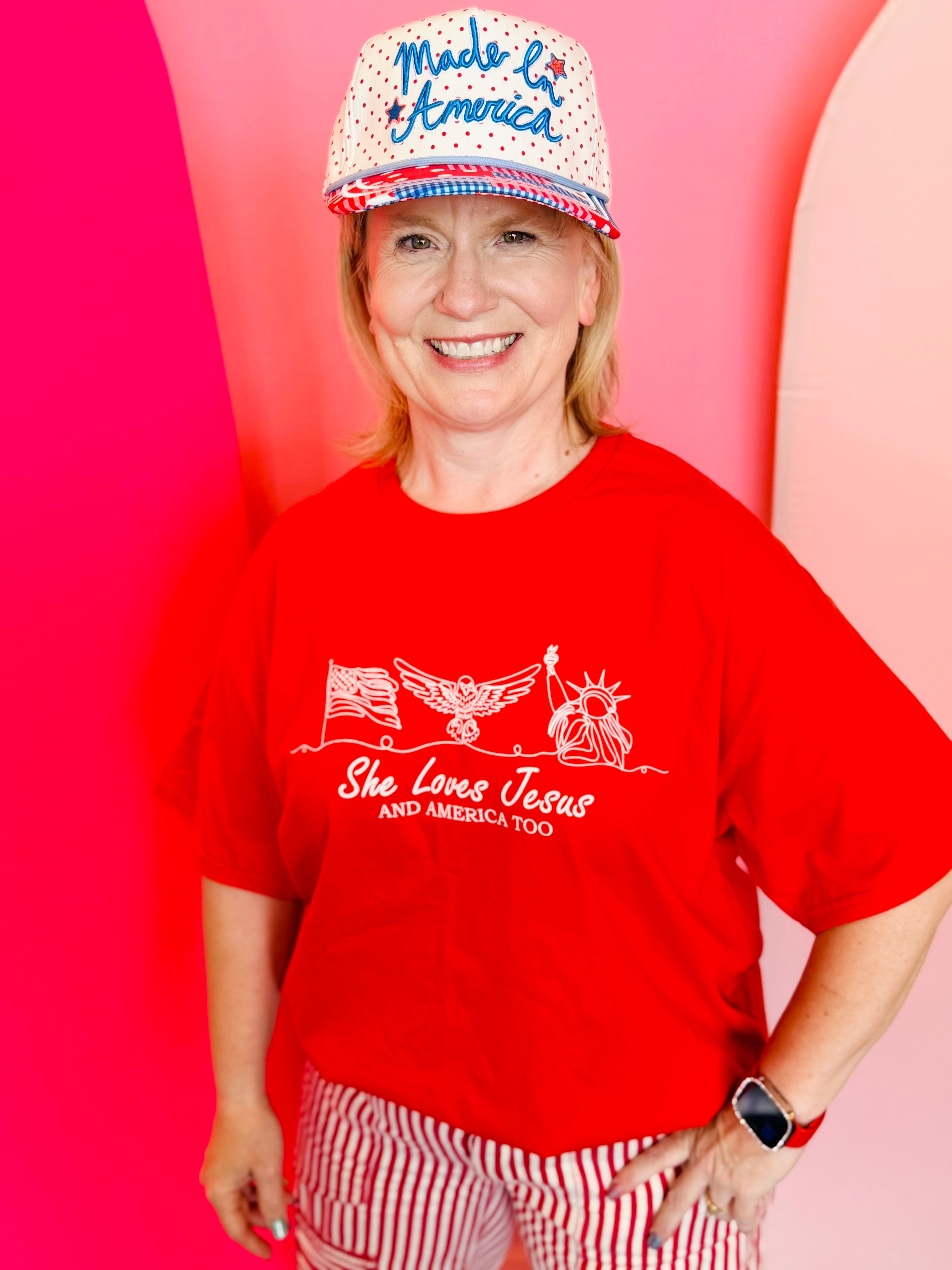 Red tee with She Loves Jesus and America Too white graphic and patriotic icons.