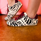 Zebra-print hair sneakers with burgundy accents and gum sole.