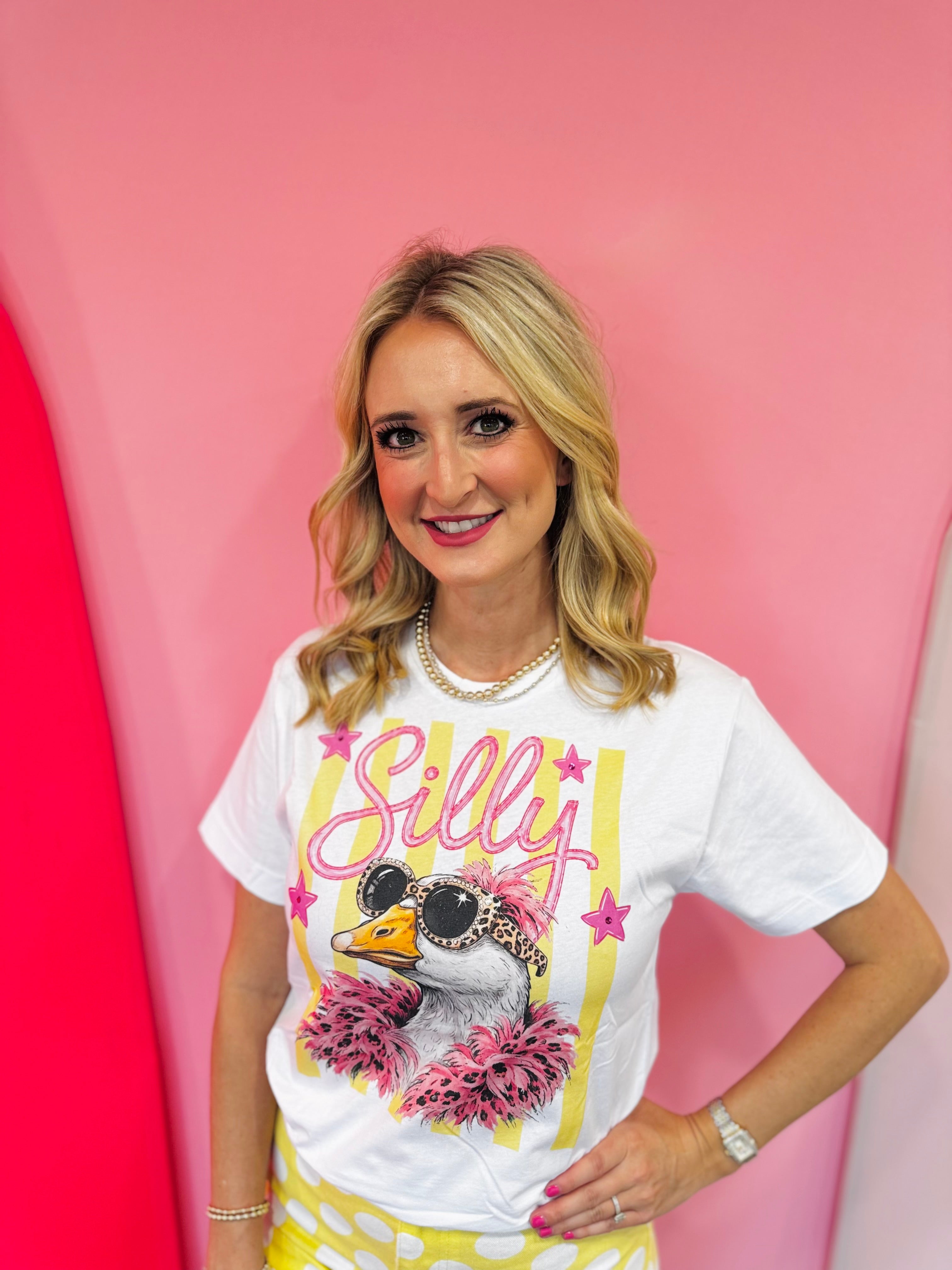 White Silly Goose graphic tee with rhinestones, leopard sunglasses, and pink feather details.