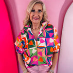 Colorful geometric print blouse with split neckline and puff sleeves.