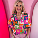 Colorful geometric print blouse with split neckline and puff sleeves.