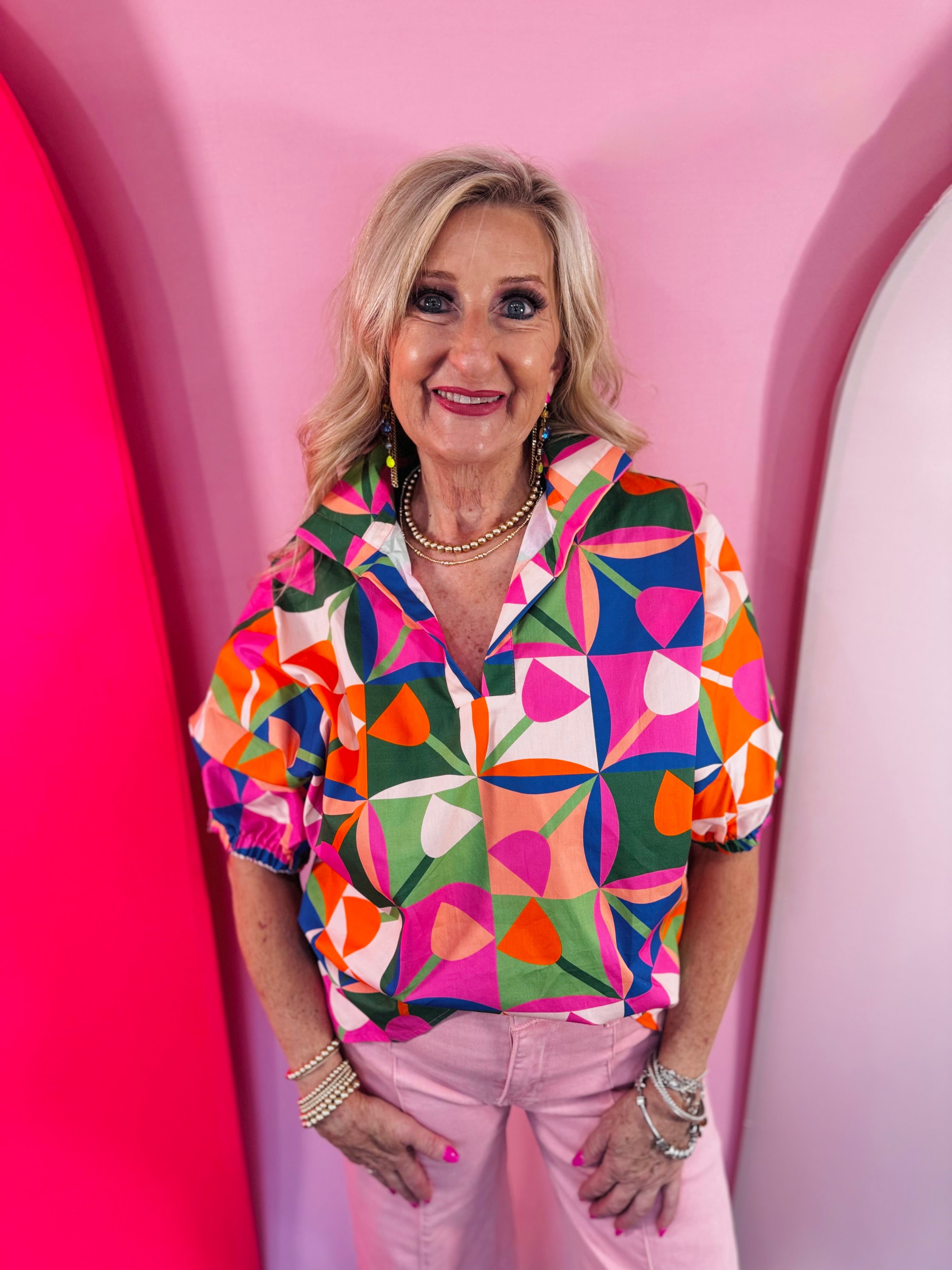 Colorful geometric print blouse with split neckline and puff sleeves.