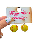 Softball dangle earrings with yellow finish, red stitching, and glossy surface.